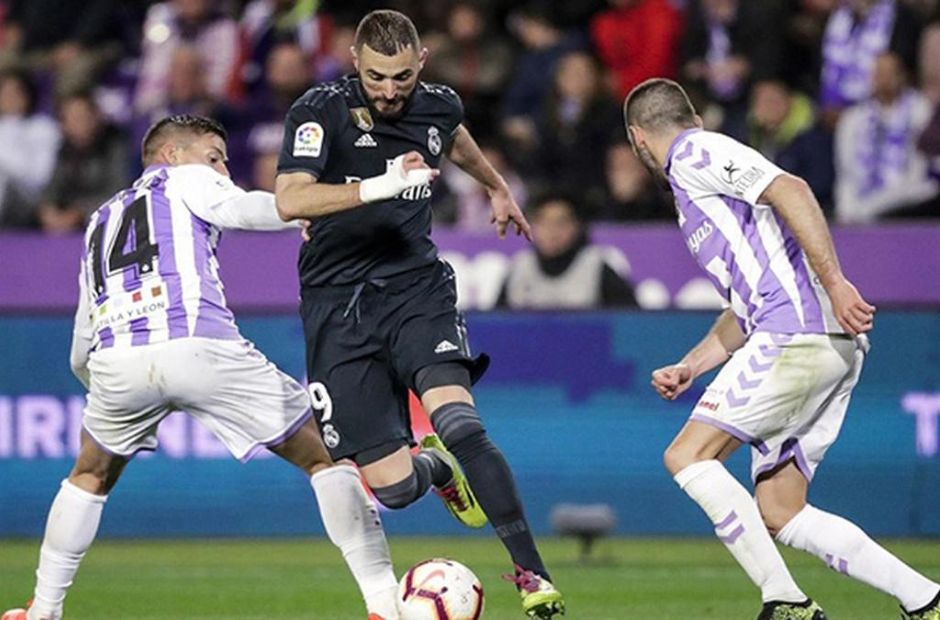 Các cầu thủ Valladolid trong trang phục áo kẻ sọc Tím-Trắng đang tranh bóng cùng cầu thủ Benzema của Real Madrid